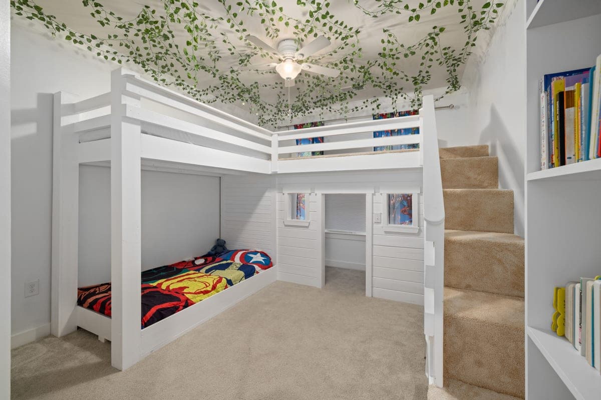 A lofted bed above a study area in a child's bedroom
