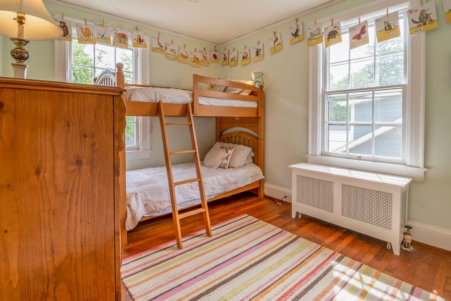 A white wooden bunk bed in a bright bedroom